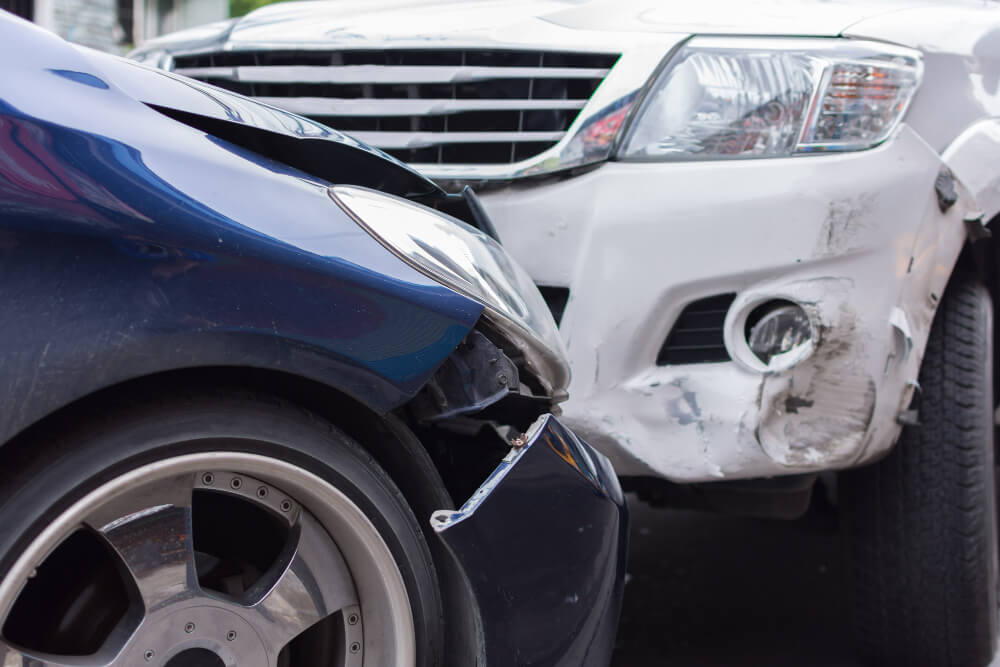 Zwei Autos, blau und weiß, stehen nach einer Kollision mit beschädigter Front für Kfz-Schadengutachten nebeneinander