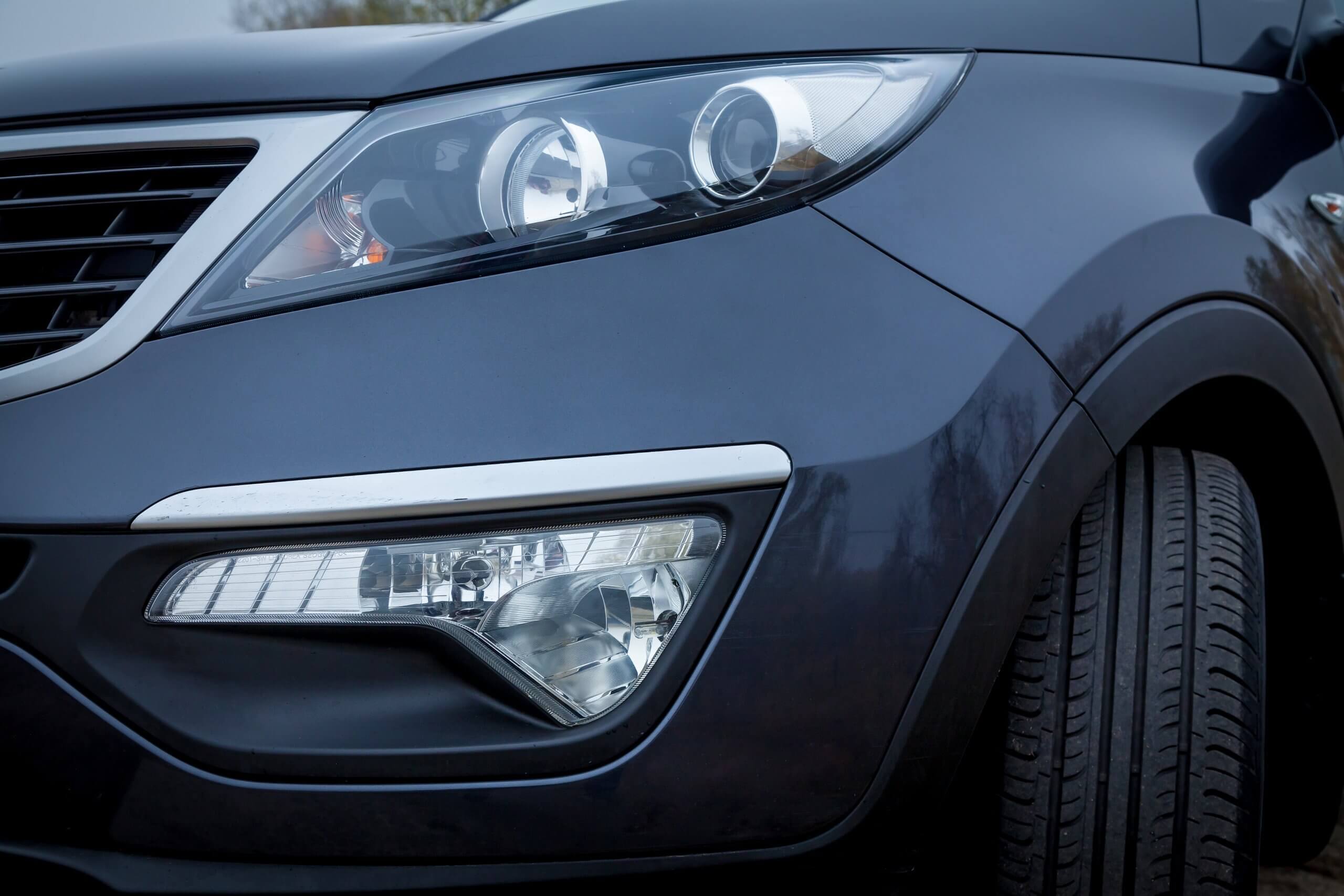 Nahaufnahme eines dunkelblauen Autos mit rechtem Frontscheinwerfer, Kühlergrill und Reifen, ein automatisch gespeicherter Entwurf im eleganten Automobildesign