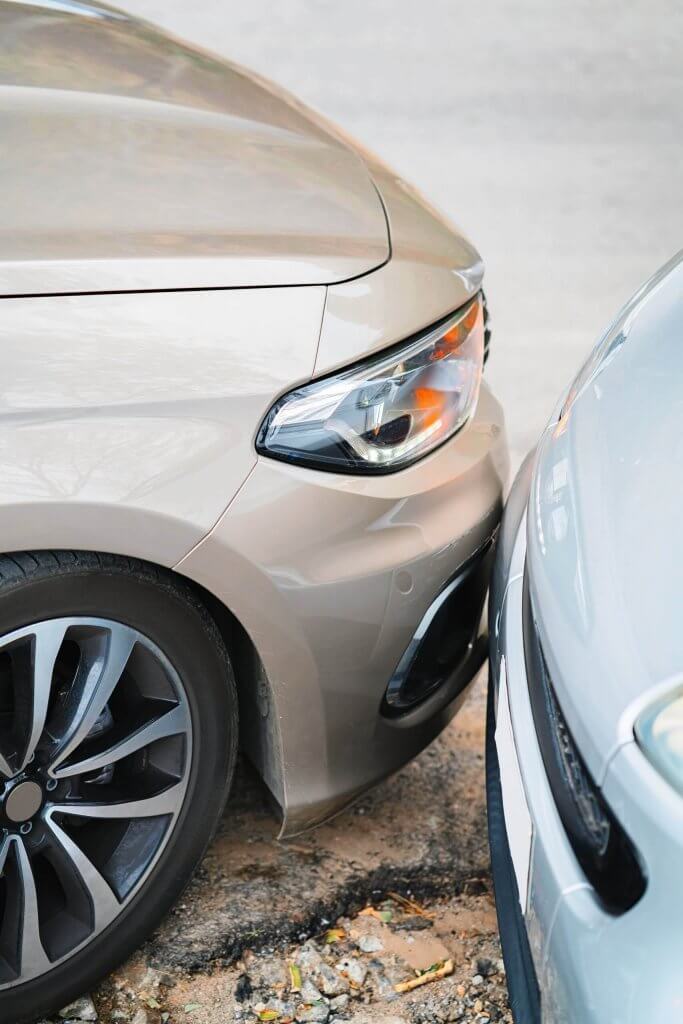 Zwei Autos stehen frontseitig auf Kies fast Stoßstange an Stoßstange nebeneinander, als spontaner Moment eingefangen