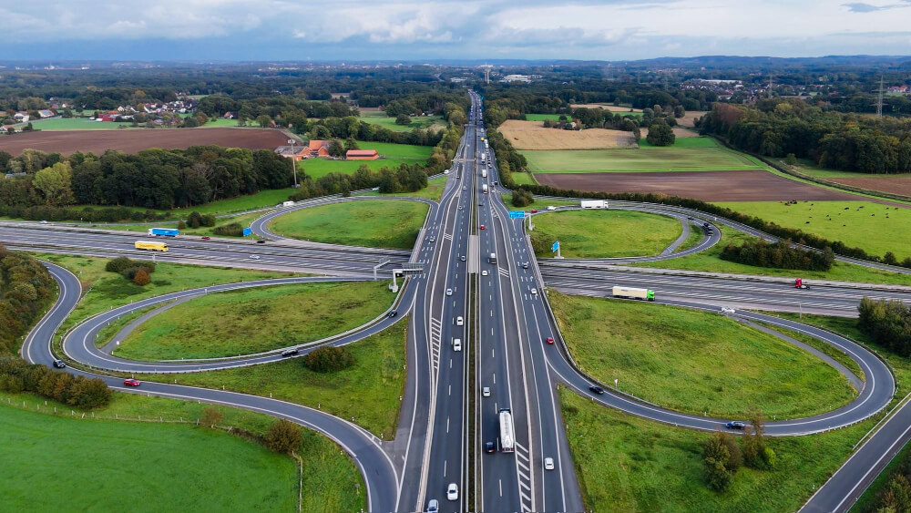 Autobahnkreuz Papenteich mit Schleifenrampen, vielen Pendlerautos und umgeben von grünen Feldern sowie landwirtschaftlichen Flächen